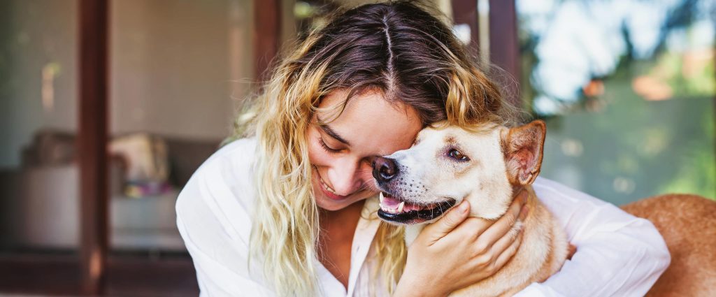 A girl happily hugs her dog